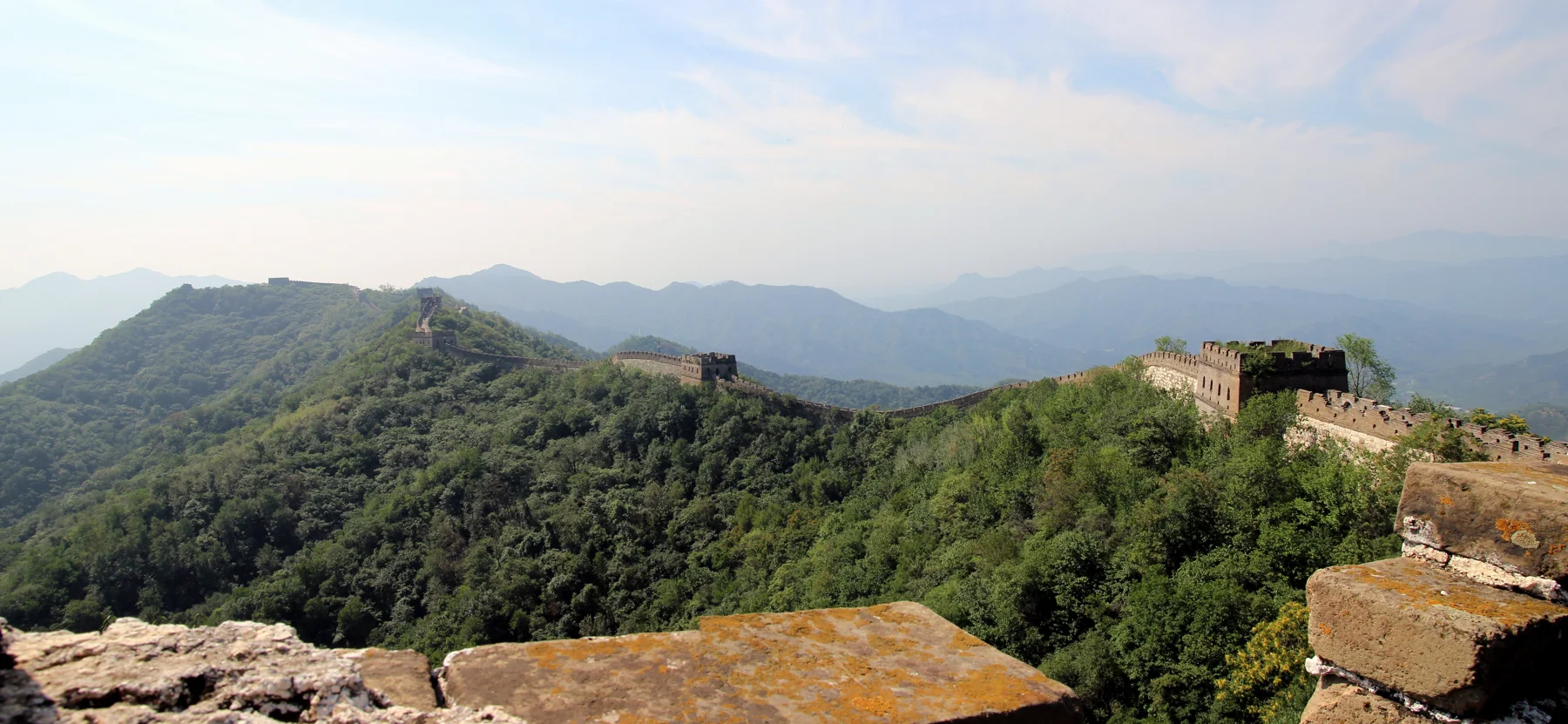The stone Great Wall and watchtowers following the wooded hills at Mutianyu