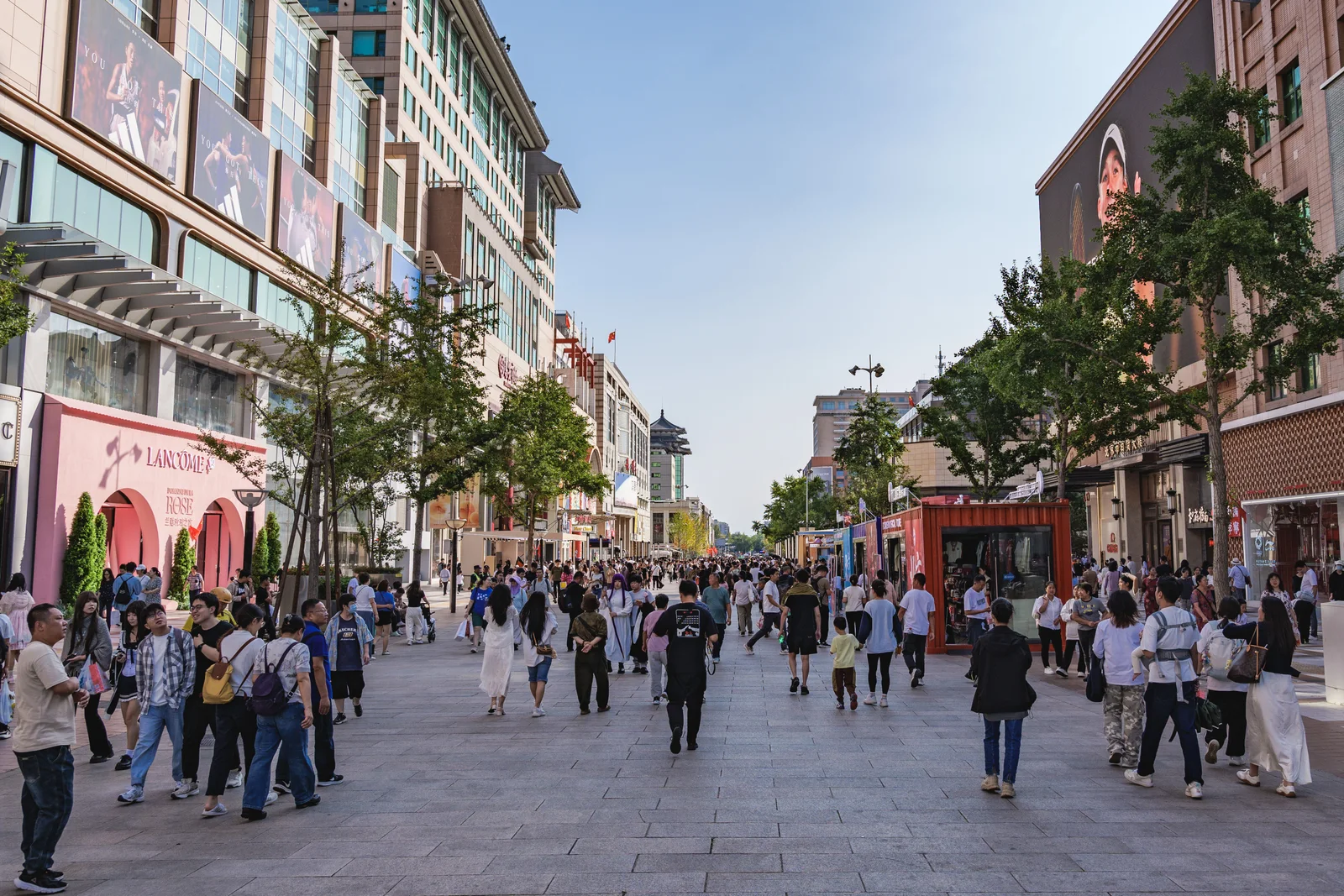 People walking along Wangfujing Street in Beijing between shopfronts and street trees